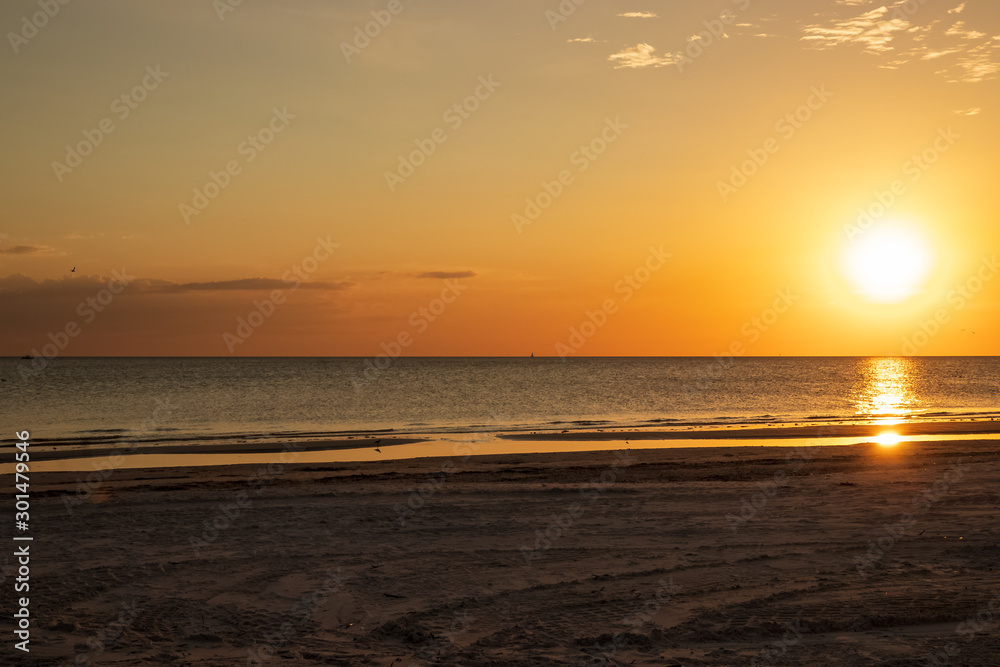 Sunset scene at Fort Myers Beach, FL, with bright orange color, sandpiper silhouette and reflection, and seagulls Sunset scene at Fort Myers Beach, FL, with bright orange color, sandpiper silhouette and reflection, and seagulls
