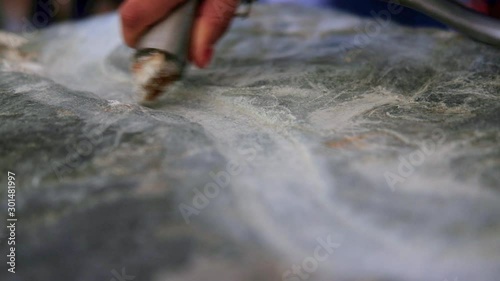 hand held close shot of hand carving a lime stone block with a wave-like pattern as a tourist attraction at Brú na Bóinne in Newgrange. Daylight situation with natural light.  photo