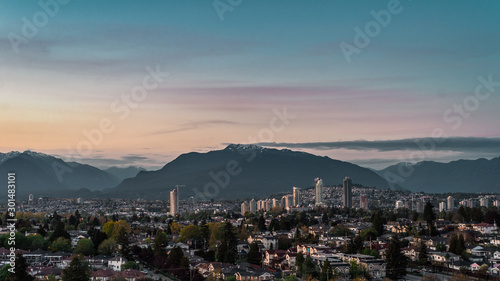 View of East Vancouver and downtown of Brentwood, Burnaby skylines with mount Seymour backdrop lit by last sun rays before sunset photo