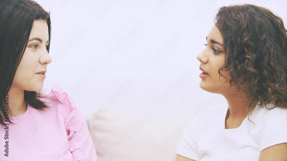 Young sweet girl friends talking carelessly, looking at the camera, posing, giving thumbs up, smiling sincerely. Young sweet girl friends talking carelessly, looking at the camera, posing, giving thumbs up, smiling sincerely.