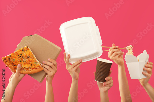 Many hands with delivery food and containers on color background