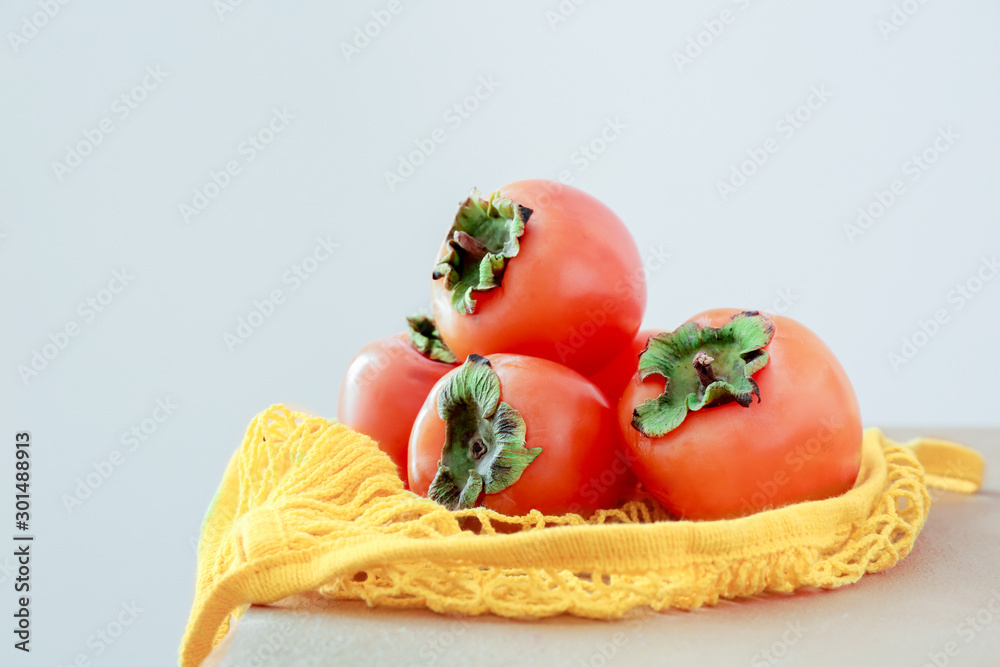 Ripe persimmons on table against light background Ripe persimmons on table against light background