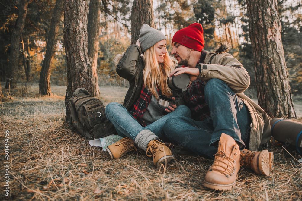 Travel couple camping with thermos in the forest. Concept of trekking, adventure and seasonal vacation. Travel couple camping with thermos in the forest. Concept of trekking, adventure and seasonal vacation.