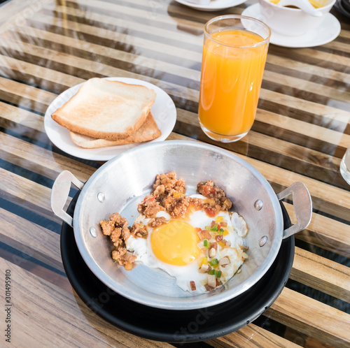 Vietnamese style fried egg in metal pan with bread and orange juice