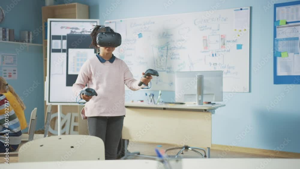 Elementary School Computer Science Class: Cute Girl Wearing Augmented Reality Headset and Using Controllers Learns Lessons in Virtual Reality Excited, Curious and Interested in Knowledge Elementary School Computer Science Class: Cute Girl Wearing Augmented Reality Headset and Using Controllers Learns Lessons in Virtual Reality Excited, Curious and Interested in Knowledge