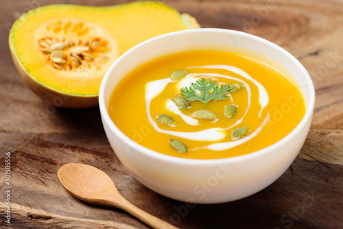 Butternut squash soup with pumpkin seed and fresh butternut squash on wooden background