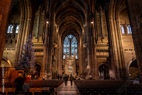 LIVERPOOL, ENGLAND, DECEMBER 27, 2018: People walking along the entrance hall of the Church of England Anglican Cathedral of the Diocese of Liverpool with a christmas tree aside during holidays. photo