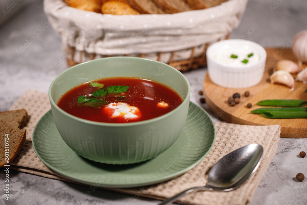 Beetroot soup with sour cream and herbs in a plate, close-up. Tasty and hearty dinner. Borsch with vegetables on a gray background. Beetroot soup with sour cream and herbs in a plate, close-up. Tasty and hearty dinner. Borsch with vegetables on a gray background.