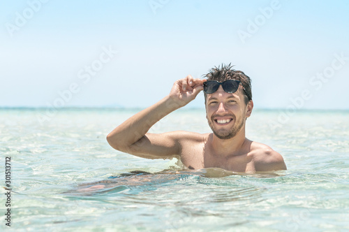 Young handsome man in sunglasses sunbathing in the azure sea. Summer vacation concept