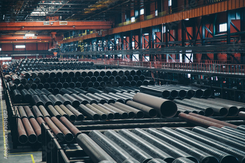 heavy industry concept, construction machinery - long metal pipes inside a large room. Building materials in the hangar