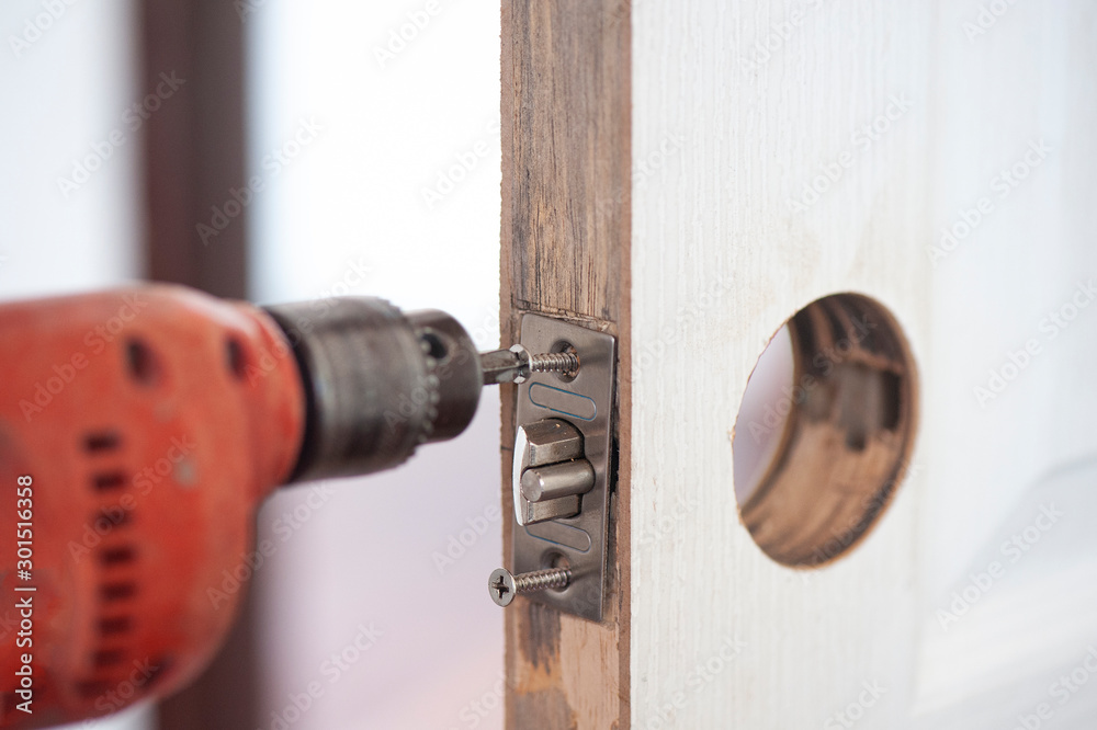 carpenter at interior wood door lock installation working with