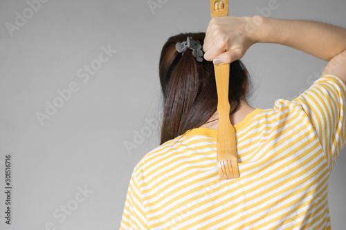 Close up woman uses a scratches to scratch his back in his house .The scratched wood