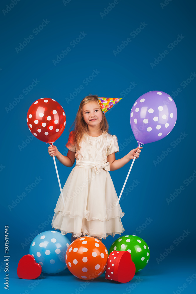 girl with gifts and balloons on the blue background. Studio portrait photos