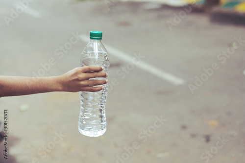Little boy hand holding bottle with fresh water