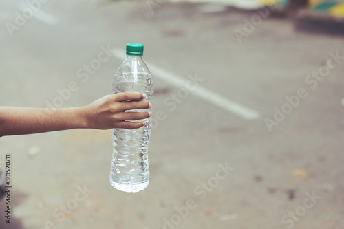 Little boy hand holding bottle with fresh water photo