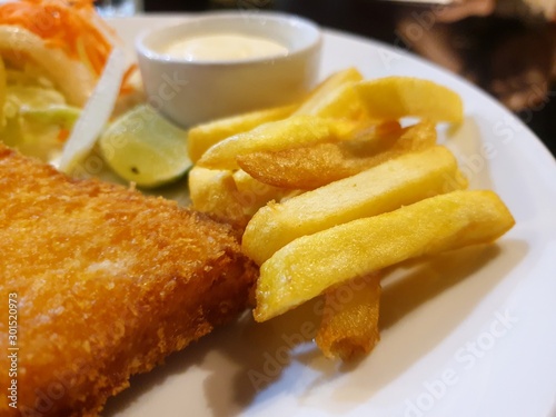 Selective focus of french fries with dory steak and mixed vegetable salad on white plate in restaurant ready to eat or serve