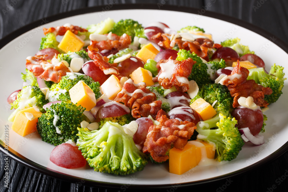 Fresh salad with broccoli, cheddar, grapes, bacon, almonds and onions with cream dressing close-up on the table. horizontal
