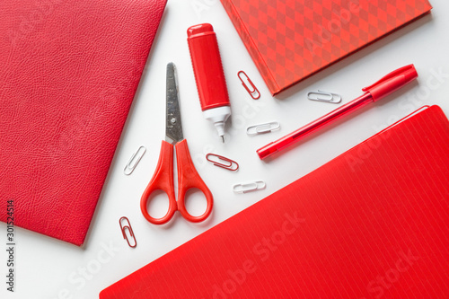 Flat lay red and white office supplies on a white background. Notebook, pen, pencil, paper clips, planer and corrector
