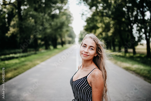 Young blond long-haired woman on a forest road, concept of new life, good future.