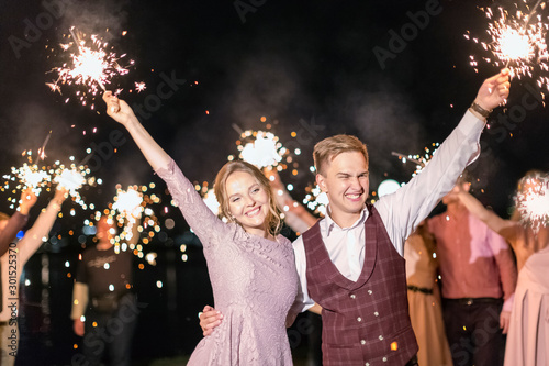 Photo Beautiful wedding finale, the bride and groom and their guests lit sparklers in