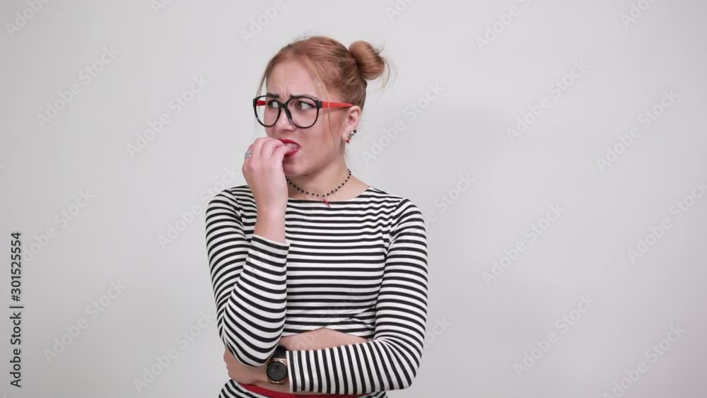 Attractive young lady wearing striped shirt and funny glasses, looking nervous and scared over isolated white background Attractive young lady wearing striped shirt and funny glasses, looking nervous and scared over isolated white background