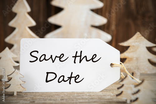 Label With English Text Save The Date. White Wooden Christmas Tree As Decoration. Brown Wooden Background