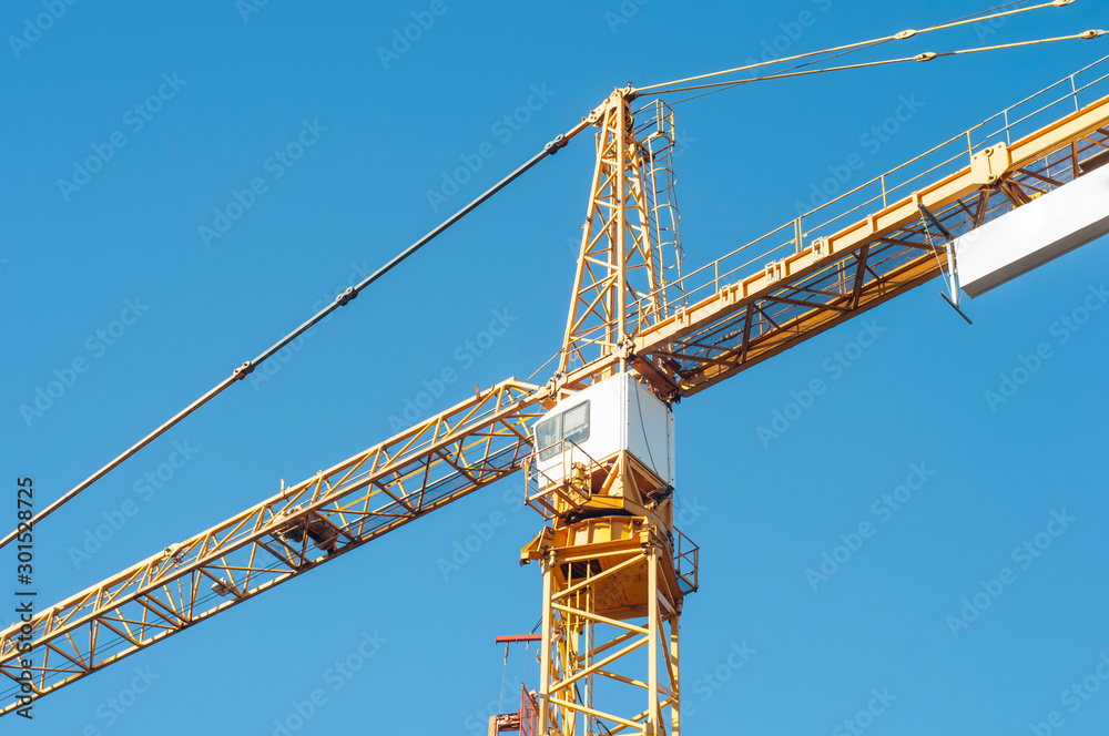 Yellow construction crane on the background of a blue sky. Yellow construction crane on the background of a blue sky.