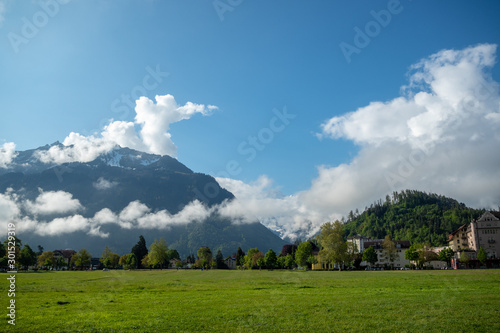 Beautiful view of green field at interlaken town on mountains and clouds blue sky background with copy space