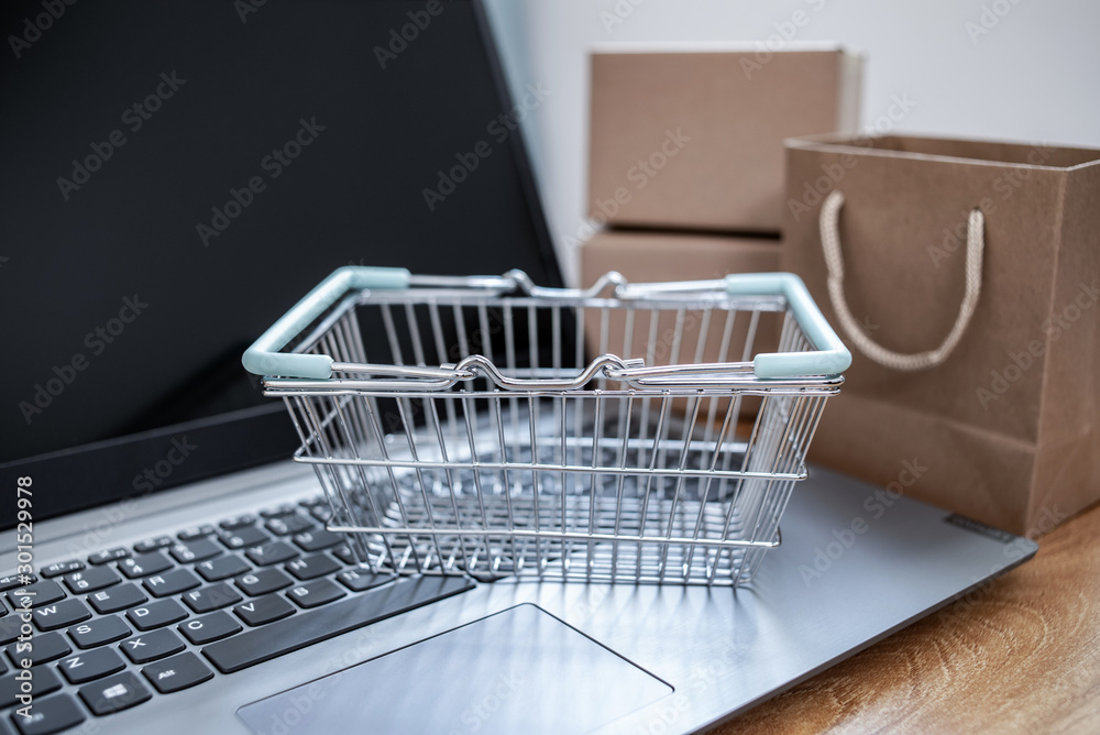 Laptop and online shopping cartons on the desk, shopping basket background material