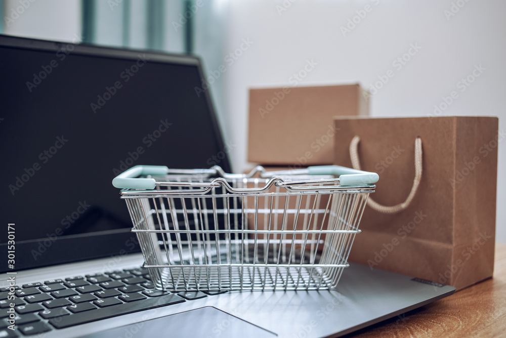 Laptop and online shopping cartons on the desk, shopping basket background material