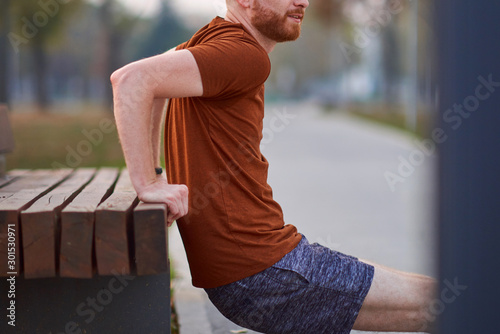 Young man exercising / stretching in urban park.
