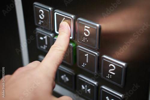 Hand of man pushing braille alphabet elevator button