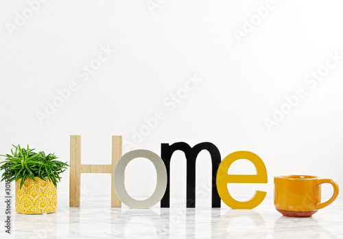 Table top with the word home, boxes for arrangement, starage, and plants in pots photo