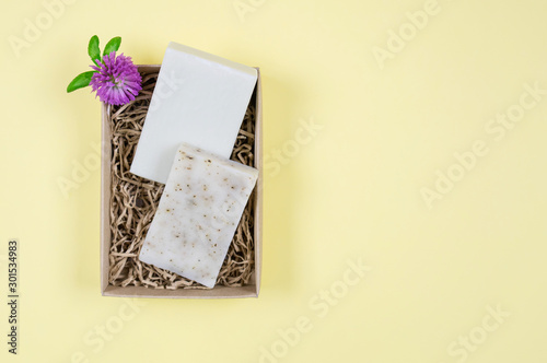 Goat milk soap in a cardboard box. Flat composition with handmade soap on a yellow background. photo