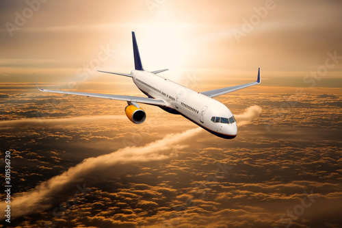 Aircraft in flight. The passenger plane flies high above the clouds during the sunset.