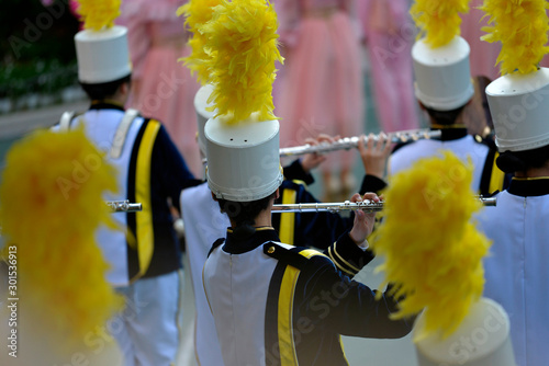 фотографія A girl is blowing a metal flute in a marching band