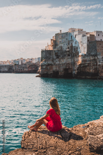 woman sitting on the beach with a view to polignano a mare, puglia, italy © Lais