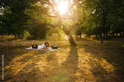 A female model is working/reading in a Public Park at sunset time