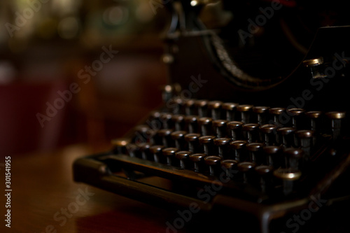 Selective focus on the keyboard key on an old black rustic typewriter on a desk in the office. The typewriter is a lot old so the letters on the keys are almost worn out. Copy space.