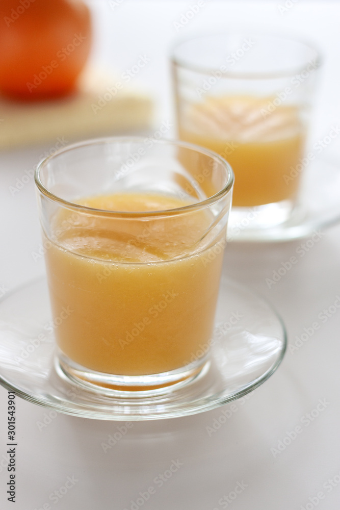 Two glasses of refreshing orange juice on a white table Two glasses of refreshing orange juice on a white table