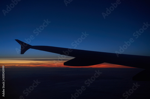 Wing of an Airbus A319 aircraft on a sunset sky.