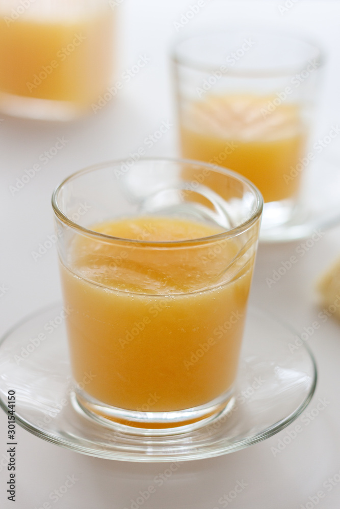 Two glasses of refreshing orange juice on a white table Two glasses of refreshing orange juice on a white table