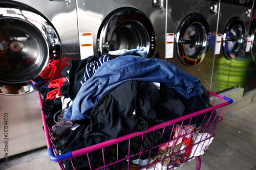 Bunch of clean laundry in a basket in front of washing machines