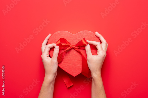 Fototapeta Close up on female hands holding a gift in a pink heart presents for valentine day, birthday, mother's day
