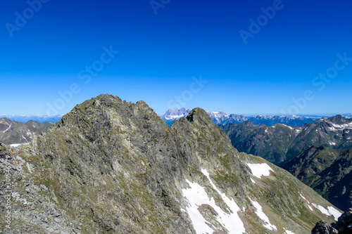 Massive, sharp stony mountain range of Schladming Alps, Austria. The mountain has a pyramid shape, it is partially overgrown with green bushes. Dangerous mountain climbing.Clear and beautiful day.