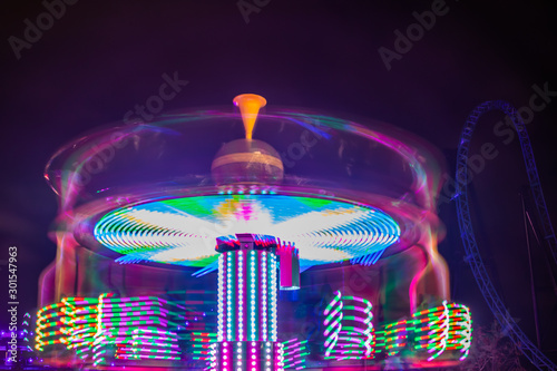 Fotografering A blurry colorful carousel in motion at the amusement park, night illumination