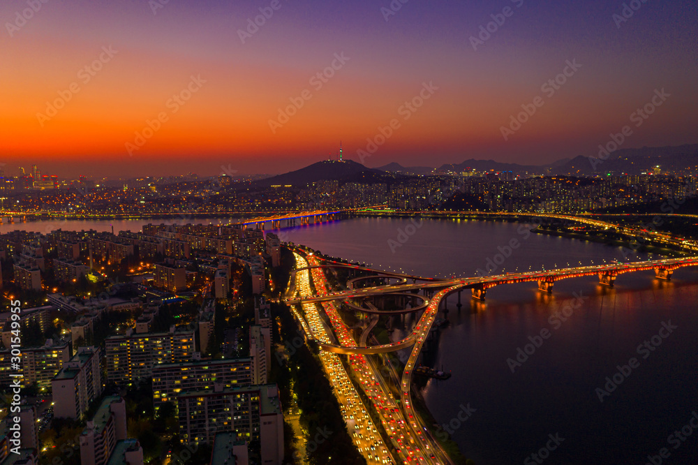 Fototapeta premium Aerial view of Seoul downtown city skyline with light trails on expressway and bridge cross over Han river at twilight sunset in Seoul city, South Korea. Aerial view of N Seoul Tower at Namsan Park