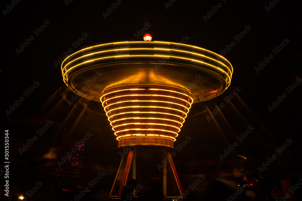 A blurry colorful carousel in motion at the amusement park, night illumination. Long exposure.