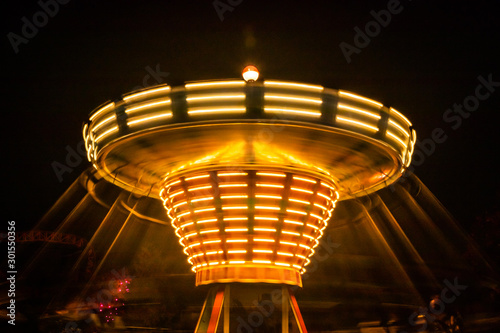 A blurry colorful carousel in motion at the amusement park, night illumination. Long exposure. photo