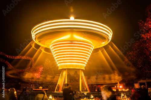 A blurry colorful carousel in motion at the amusement park, night illumination. Long exposure. photo